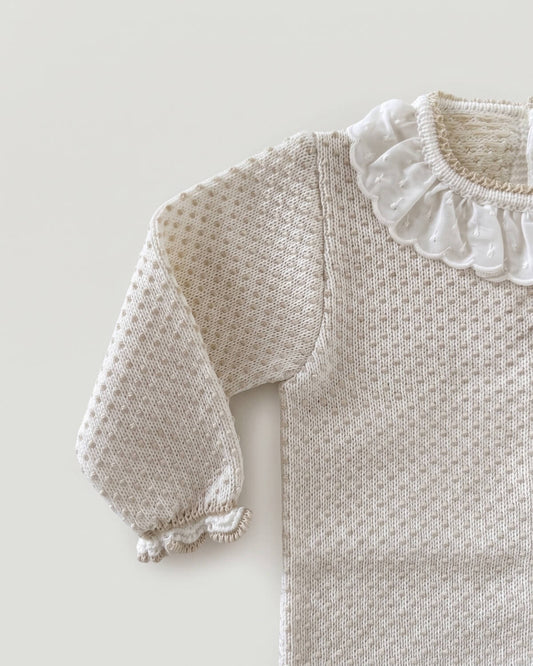 Close-up detail of frilled lace collar and textured knit on beige Spanish baby jumper
