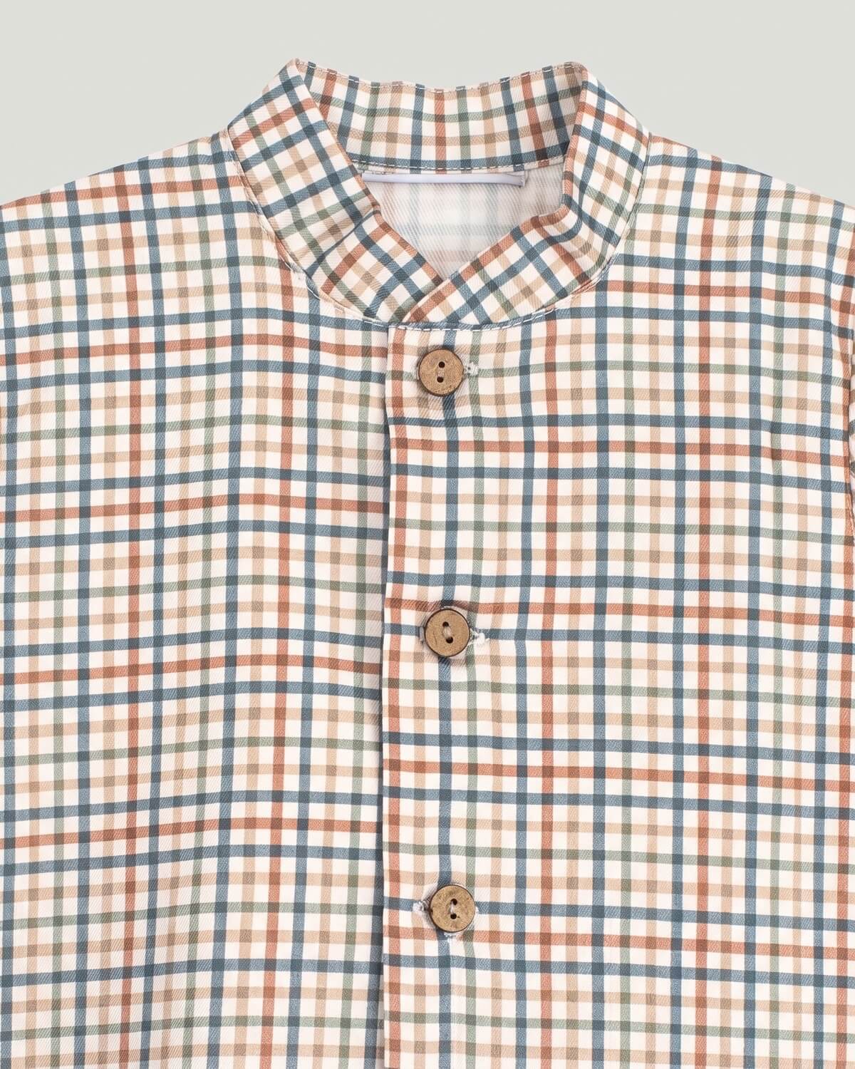 Close-up detail of checked pattern, grandad collar and wooden buttons on Spanish baby boy shirt.
