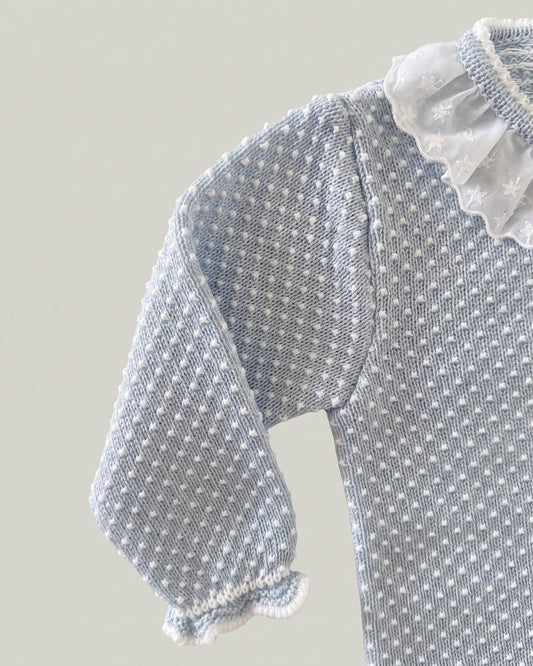 Close-up detail of organza frill collar and polka dot knit texture on light blue Spanish baby jumper.
