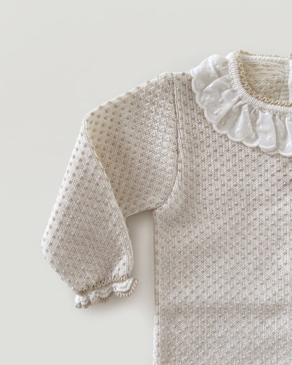 Close-up detail of frilled lace collar and textured knit on beige Spanish baby jumper
