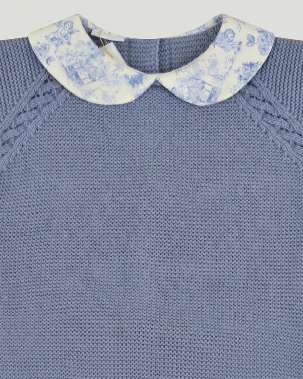 Close-up detail of Peter Pan toile de Jouy collar and raglan sleeve knit pattern on baby blue jumper.