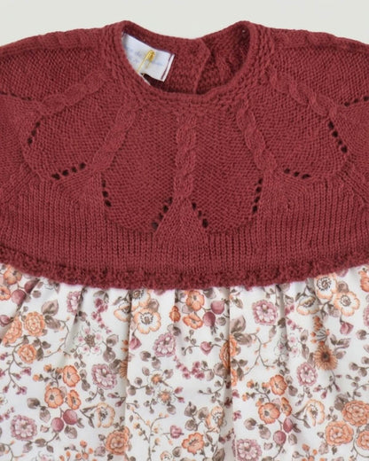 Detail of burgundy knitted bodice with delicate eyelet stitch and floral printed fabric on Spanish baby dress.