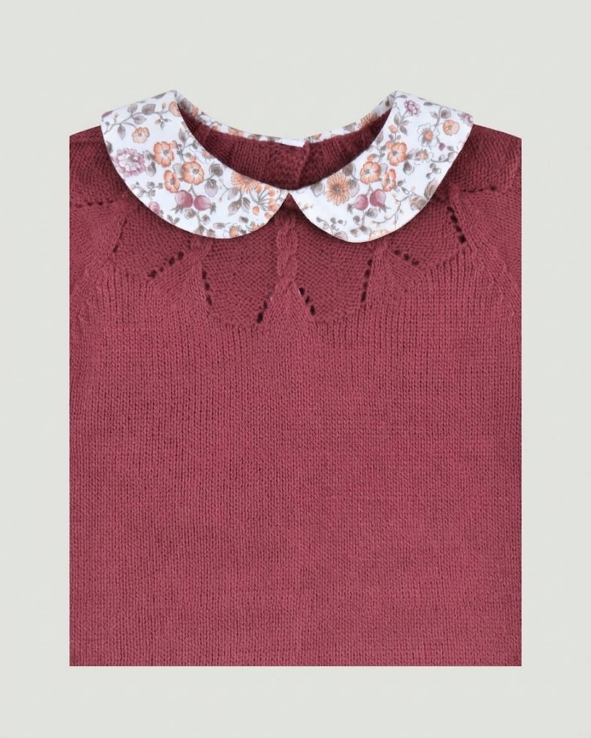 Close-up detail of floral printed Peter Pan collar and delicate eyelet knit yoke on burgundy baby jumper.