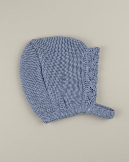 Detail view of traditional Spanish baby bonnet in dusty blue knit with lace edge.