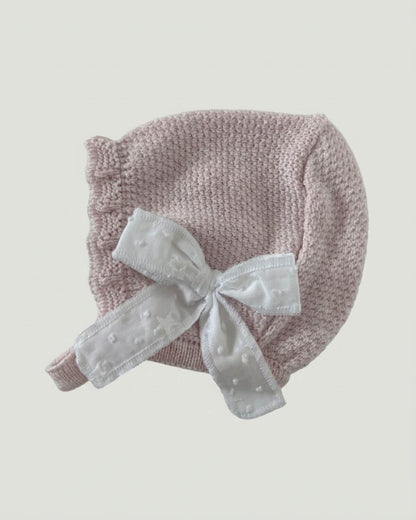 Matching pale pink knitted baby bonnet featuring a white star ribbon bow detailing.L