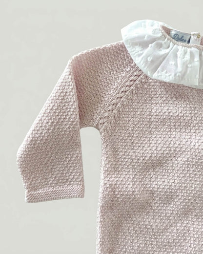 Folded pale pink knitted baby jumper with white embroidered star frill collar.