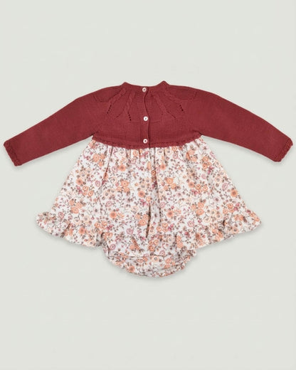 Back view of traditional Spanish baby dress showing burgundy knitted yoke with button closure and floral print skirt.