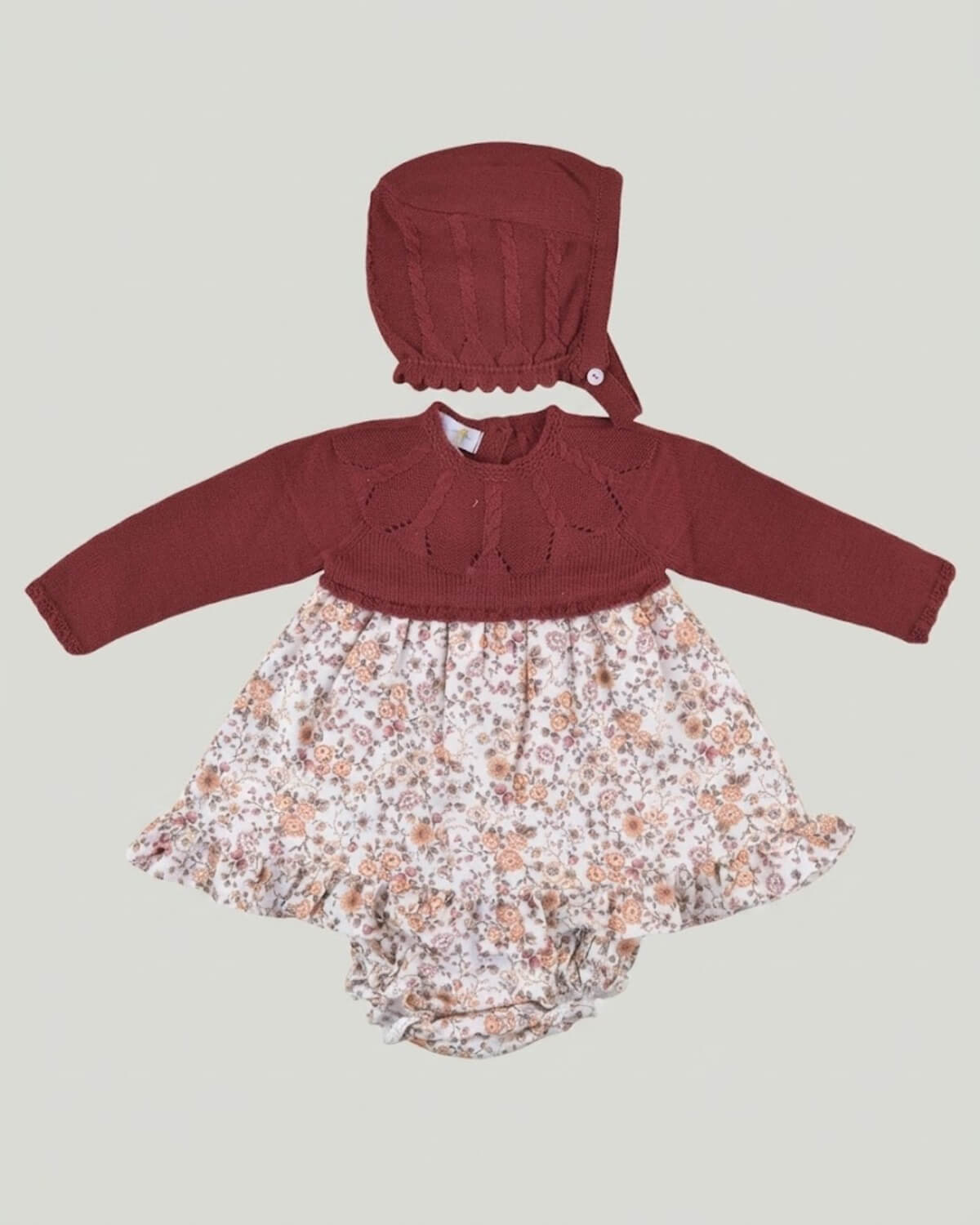 Dulce de Fresa traditional Spanish baby girl dress set featuring burgundy knitted bodice, floral skirt, bloomers and bonnet.