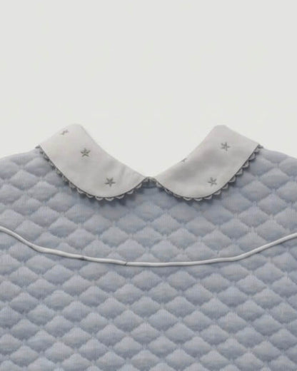 Close-up detail of Peter Pan collar with embroidered stars on blue quilted baby top.